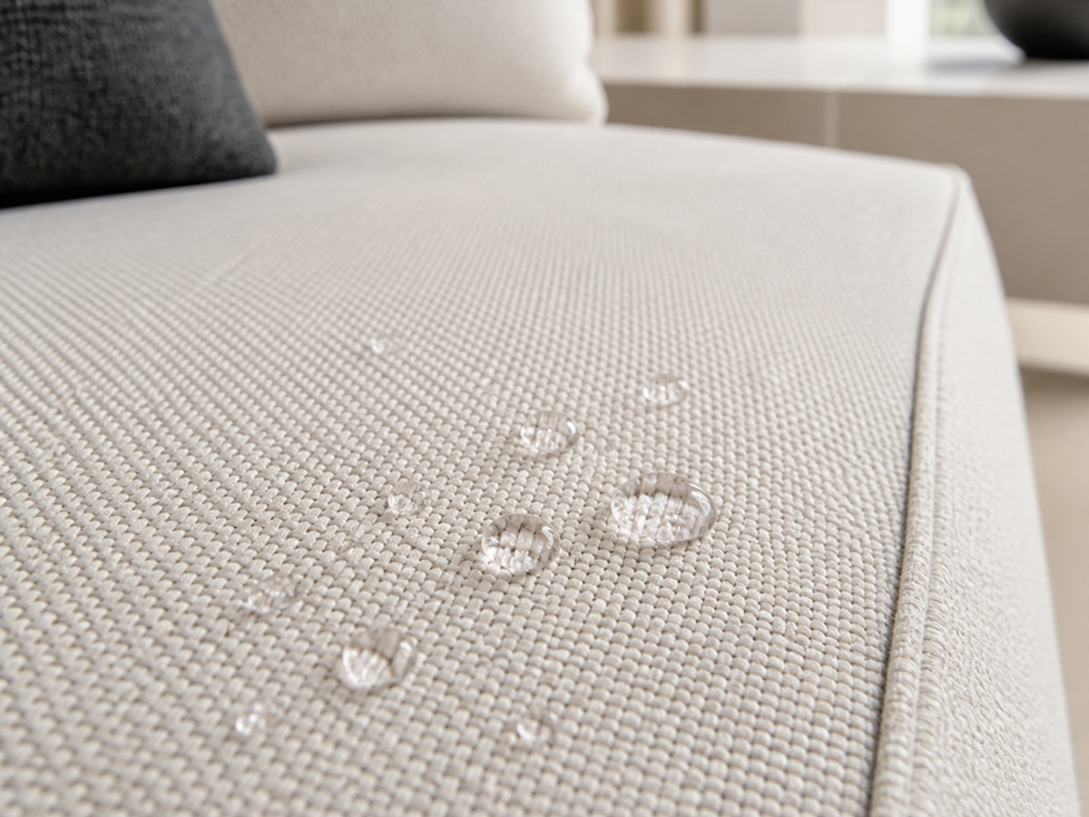 Water droplets beading on a light grey flat weave sofa seat